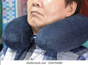 Southeast Asian, Chinese Old Man Taking A Nap On Neck Pillow During Daytime In His Home. Tiredness Can Cause Sleepy.