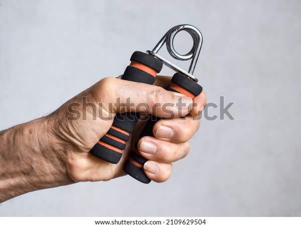 Southeast asian, Chinese old man gripping hand\
exercise gripper.