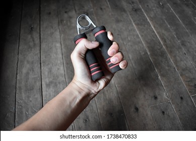 Southeast asian, Chinese young man’s right hand gripping hand exercise gripper.
