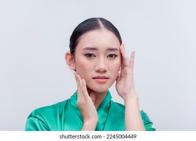 Southeast Asian female executing the popular migraine selfie hand pose for a studio photo shoot isolated on a white background. Young woman putting her hands on her smooth face. Iconic headache pose. - Shutterstock ID 2245004449
