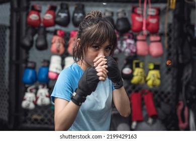 A Southeast Asian female MMA athlete puts her game face on as she poses for the camera showing the correct fighting position. - Shutterstock ID 2199429163