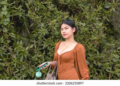 A Southeast Asian female poses for the camera in front of the garden hedge as she puts on a fierce look. - Shutterstock ID 2206235897