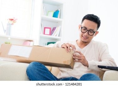 Southeast Asian Male Received An Express Parcel And Open It At Home