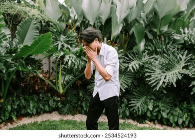 A Southeast Asian man captured mid-sneeze, his eyes closed and mouth open, with one hand covering his face. The moment highlights a natural reflex in an everyday setting - Powered by Shutterstock