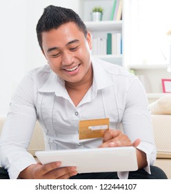 Southeast Asian Man Online Shopping, Hands Holding Credit Card And Computer Tab Sitting At Home.