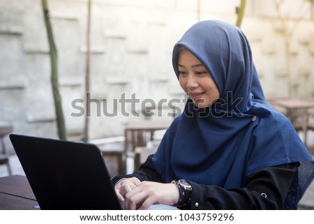 Southeast asian muslim women with hijab using laptop at the outdoor cafe