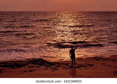 Southeast Asian young man with shadow looking for help at the sunset on the beach of a desert island. Silhouette image of Castaway man. Shipwrecked and stranded. - Shutterstock ID 1421340053