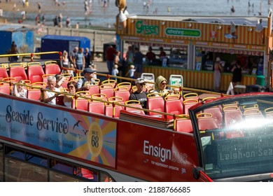 Southend-on-Sea, UK  August 10th 2022  Open top bus, top deck with passengers, on a beachfront road at the English seaside in Essex, England. Red bus, close up, from above, sunny, bright heatwave, hot