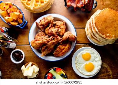 Southern Brunch Table, With Buttermilk Fried Chicken, Homemade Stack Of Pancakes Waffles Home Fries W/ Onions & Peppers, Sunny Side Up Farm Fresh Eggs, Crispy Bacon, Sausage Links, Coffee, OJ & Butter