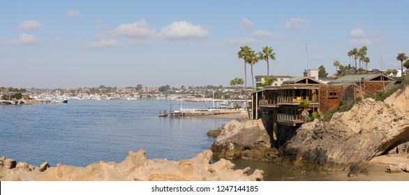 Southern California Coastline. View Of The Coastal Access To The Newport Beach Harbor From A Rocky Cliff. Cityscape Of The Marina Seen From Pirates Cove In Corona Del Mar, California