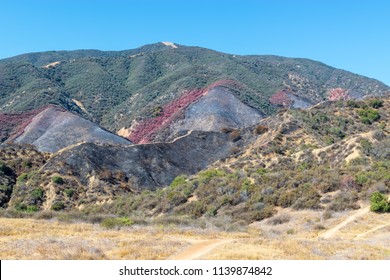 Southern California Mountains Show Damage From Recent Wildfire With Fire Retardant And Burned Hillsides In Bright Summer Sunshine