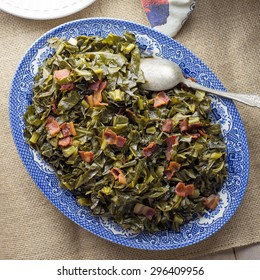 Southern Style Collard Greens With Bacon Served On An Antique Plate With Burlap Table Runner.  