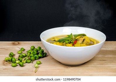 Southern Thai Spicy Sour Yellow Curry with bamboo shoot preserved and striped snakehead fish in a white cup on a wooden table.