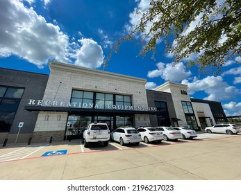 SOUTHLAKE, TX, US-AUG 28, 2022: Green Oak Leaves And Wide Angle View Exterior Entrance Of REI (Recreational Equipment, Inc) Store With Parked Cars In Front Under Sunny Cloud Blue Sky