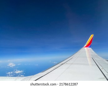 Southwest airplane wing flying above the clouds on a brigh blue sky sunny day.