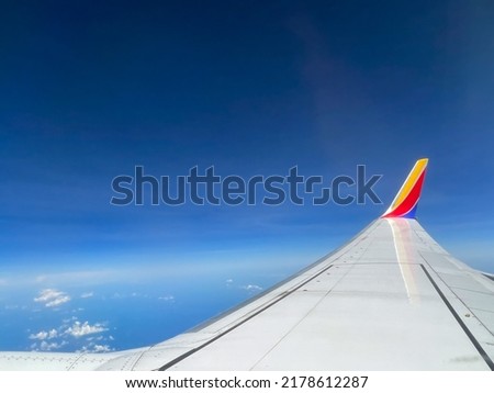 Southwest airplane wing flying above the clouds on a brigh blue sky sunny day.
