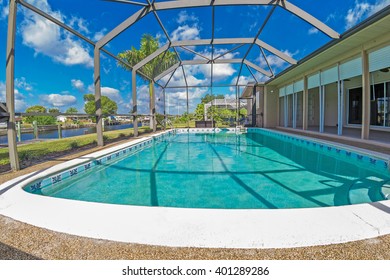 Southwest Florida homes on a canal.  View of canal homes through the screened cage surrounding the pool in one of the homes, and lanai on the right. 