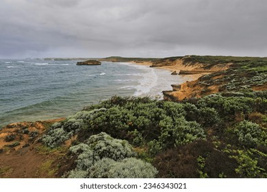 Southwest-northeast view to the sea stack in the middle of the beach at the Bay of Martyrs southeasternmost end along the Shipwreck Coast-Great Ocean Road on a cloudy, rainy morning. VIC-Australia.