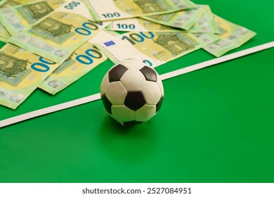 A souvenir soccer ball against a background of hundred-euro banknotes on a green background, sports betting, football match bets, sports betting, bookmaker bets, яяbetting odds. - Powered by Shutterstock