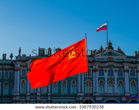 Soviet Union flag with the Russian flag and the Hermitage Museum in the background. In St. Petersburg, Russia 