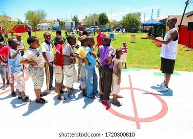 Soweto, South Africa - December 11, 2010: African Children Lining Up To Take Turns To Take A Goal Shot On Public Playground Basketball Court