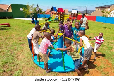 Soweto, South Africa - December 11, 2010: African Kids Playing Merry Go Round And Other Park Equipment At Local Public Playground