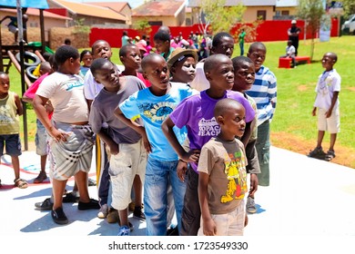 Soweto, South Africa - December 11, 2010: African Children Lining Up To Take Turns To Take A Goal Shot On Public Playground Basketball Court