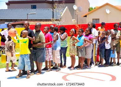 Soweto, South Africa - December 11, 2010: African Children Lining Up To Take Turns To Take A Goal Shot On Public Playground Basketball Court