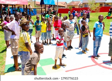 Soweto, South Africa - December 11, 2010: African Children Lining Up To Take Turns To Take A Goal Shot On Public Playground Basketball Court