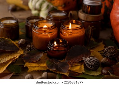 Soy candles burn in glass jars. Tree leaves. Comfort at home. Candle in a brown jar. Scent and light. Scented handmade candle. Aroma therapy. Autumn mood. Cozy home decor in fall. Festive decoration. - Shutterstock ID 2286331899