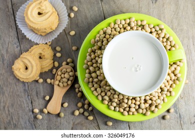 Soy Milk [Soya Milk ] In Green Cup And Soy Bean In Wooden Spoon With Cookies On Wooden Table Background. Top View.