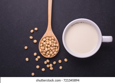 Soy milk in white cup and soy bean on dark table background. Top view