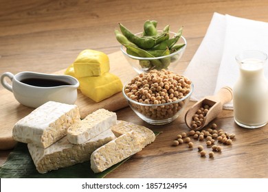 Soy Product: Raw Tofu, Tempeh, Soy Milk, Soy Sauce, And Soy Bean. Concept Of Healthy Vegetarian Food. On Wooden Brown Background 