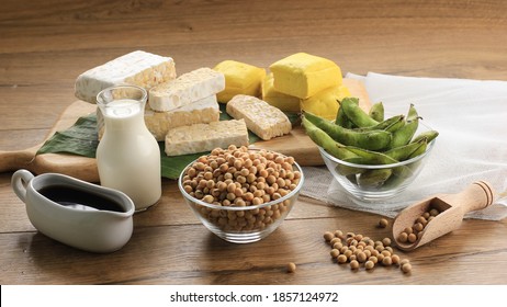 Soy Product: Raw Tofu, Tempeh, Soy Milk, Soy Sauce, And Soy Bean. Concept Of Healthy Vegetarian Food. On Wooden Brown Background 