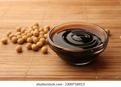 Soy sauce in bowl and soybeans on bamboo mat, closeup - Powered by Shutterstock