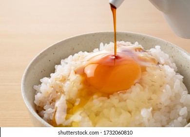 Soy sauce on rice with egg set against a wooden backdrop