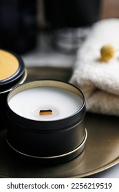 Soy scented candles in metal jars, boxes. Candles on a metal tray. in front of a bathtub. Modern hobby handmade, paraffin free coconut wax candles. Wooden wick. 