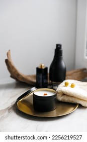 Soy scented candles in metal jars, boxes. Candles on a metal tray. in front of a bathtub. Modern hobby handmade, paraffin free coconut wax candles. Wooden wick. 