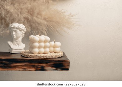 Soy wax candle on a textured table. Interior decor with a handmade burning candle. Hygge home decoration concept and aromatherapy. Bubble candle on the background of a textured wall.Place for text.