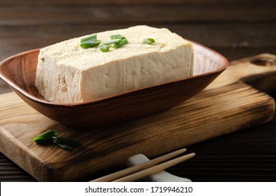 Soybean tofu vegetable bean curd in clay bowl on kitchen table with chives and chopsticks aside
