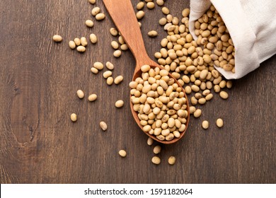 Soybeans Scattered On Rustic Table With Wooden Spoon From Paper Bag, Top View, Free Space