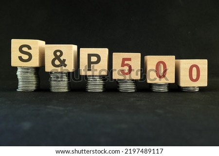 SP 500 stock market index crash and bear market due to financial crisis and recession in US. Wooden blocks in with coins in dark black background.
