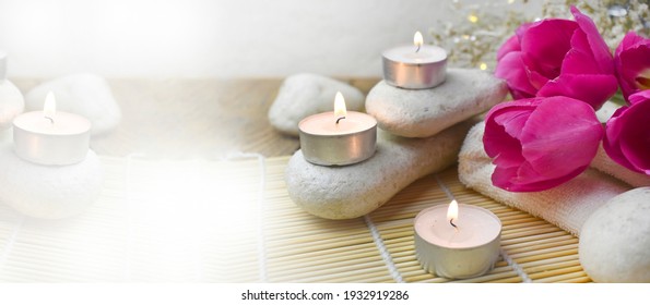 Spa Aromatherapy Massage Composition With Pebbles, Tulips, Burning Candles. Springtime Wellness Concept. Relaxation. Greeting Banner For Mothers Day Or Wedding.