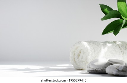 Spa background concept. Towel and stones on a white background with hard shadows, with leaves. The concept of body care and relaxation, treatment. - Powered by Shutterstock