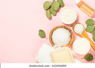 Spa Background With Natural Cosmetics, Sea Salt, Clay Mask, Towel, Sponge And Cosmetic Oil. Top View On Pink Background.