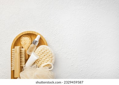 Spa and bathroom accessories on wooden tray, brush, oil, cream, bath sea salt on wooden spoon, towel. Spa and massage products set conception. Top veiw, white background