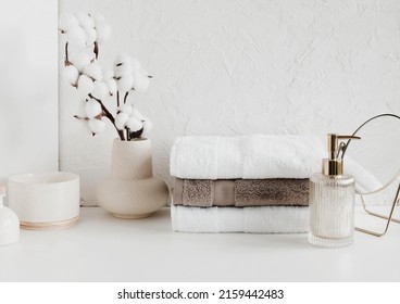 Spa, bathroom background. Towels on white desk near white wall and interior accessories with copy space.  Neutral beige colors. - Shutterstock ID 2159442483