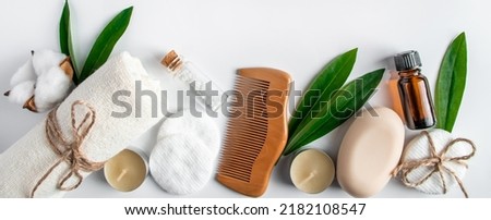 Spa body care accessories on white background. Towel, hairbrush, essential oil. Cosmetic products concept. Flat lay composition. Copy space, banner format.