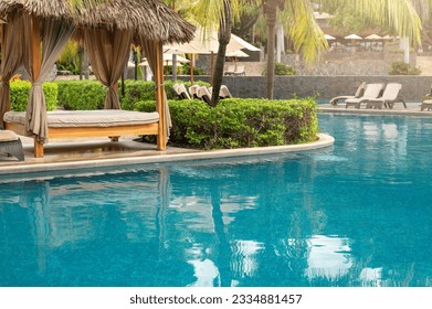 Spa cabana next to blue pool outside of luxury hotel resort