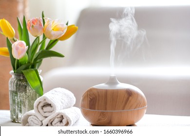 Spa composition with the aroma of a modern oil diffuser with body care products . Twisted white towels, spring greens and flowers. Spa concept for body and health care .